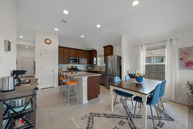 311 Spiny Lizard Ln, San Marcos, TX 78666 - kitchen with stainless steel appliances, a kitchen island, lofted ceiling, a sink, and a kitchen breakfast bar