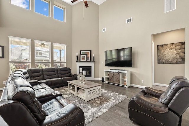 19325 Tristan Stone Dr, Pflugerville, TX 78660 - living room with a ceiling fan, a high ceiling, a glass covered fireplace, and wood finished floors