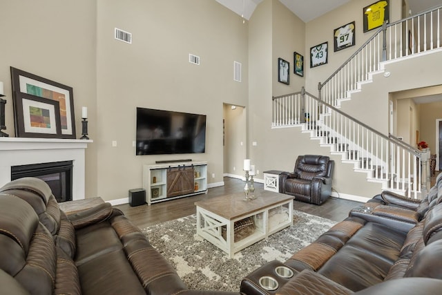 19325 Tristan Stone Dr, Pflugerville, TX 78660 - living area featuring a high ceiling, wood finished floors, stairs, and a glass covered fireplace