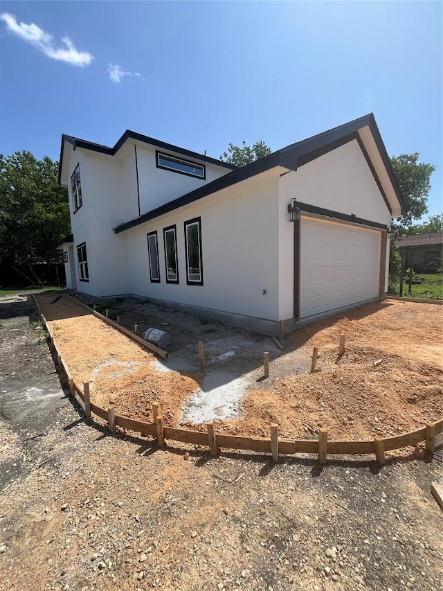 401 E Carrie St, Manor, TX 78653 - view of home's exterior with stucco siding, an attached garage, and dirt driveway