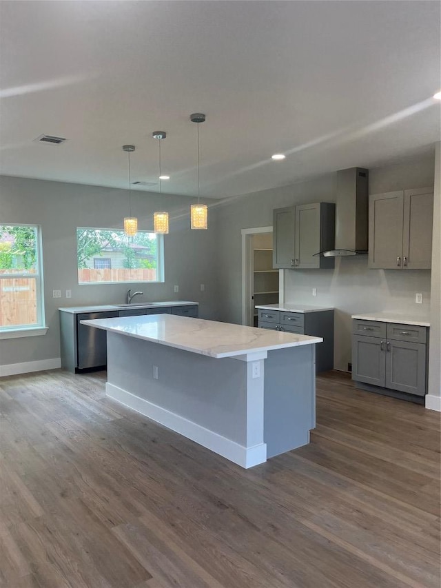 401 E Carrie St, Manor, TX 78653 - kitchen featuring wall chimney exhaust hood, stainless steel dishwasher, dark wood-style floors, a kitchen island, and gray cabinetry