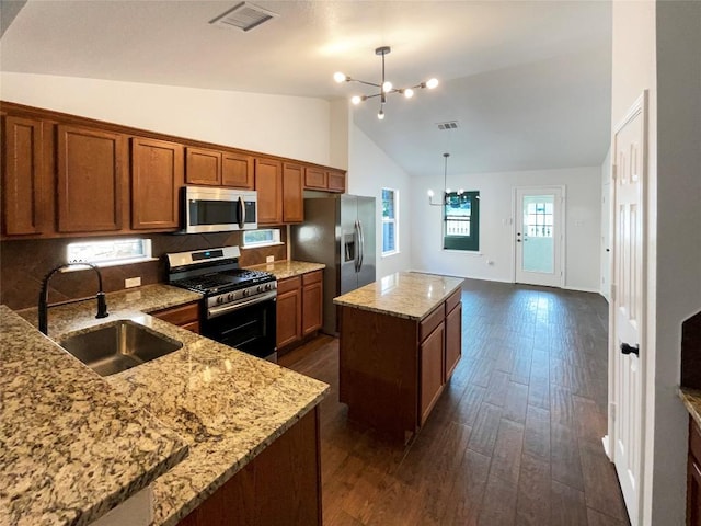 18132 Great Basin Ave, Pflugerville, TX 78660 - kitchen with appliances with stainless steel finishes, a chandelier, a kitchen island, brown cabinetry, and dark wood finished floors