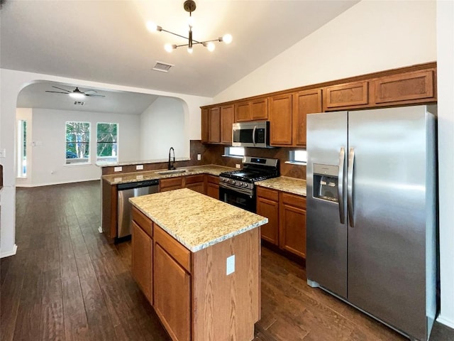 18132 Great Basin Ave, Pflugerville, TX 78660 - kitchen featuring appliances with stainless steel finishes, arched walkways, a kitchen island, a peninsula, and vaulted ceiling