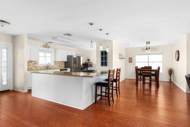 235 El Camino River Rd, Bastrop, TX 78602 - kitchen featuring stainless steel fridge, dark wood-type flooring, white cabinets, and a kitchen breakfast bar