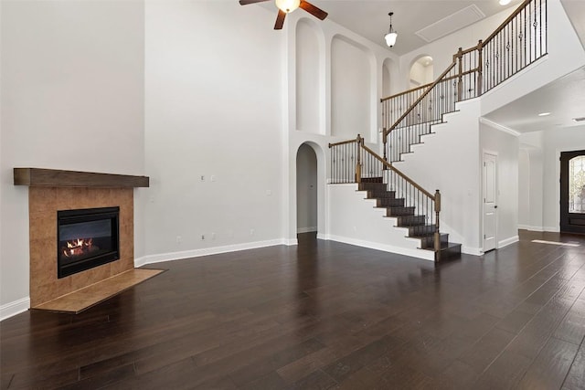 8508 Lookout Cliff Pass, Austin, TX 78737 - unfurnished living room featuring wood finished floors, a towering ceiling, a tile fireplace, baseboards, and a ceiling fan