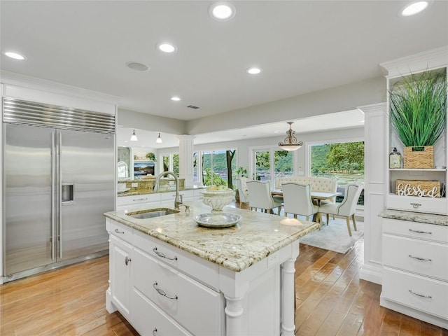14753 Arrowhead Dr, Austin, TX 78641 - kitchen with built in fridge, a sink, white cabinetry, light wood-style floors, and an island with sink