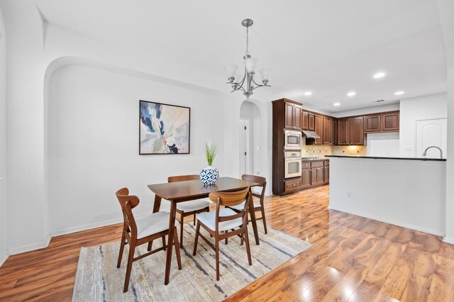 8328 Alophia Dr, Austin, TX 78739 - dining area with arched walkways, recessed lighting, light wood-style flooring, a chandelier, and baseboards
