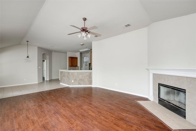 728 Stokesay Castle Path, Pflugerville, TX 78660 - unfurnished living room with light wood-style flooring, vaulted ceiling, a fireplace, a ceiling fan, and arched walkways