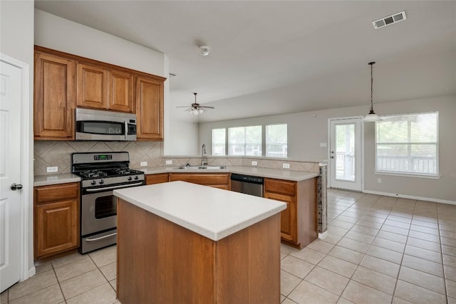 728 Stokesay Castle Path, Pflugerville, TX 78660 - kitchen with appliances with stainless steel finishes, light tile patterned floors, brown cabinets, a peninsula, and light countertops