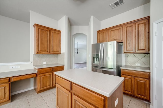 728 Stokesay Castle Path, Pflugerville, TX 78660 - kitchen featuring stainless steel fridge, light tile patterned floors, brown cabinetry, and decorative backsplash