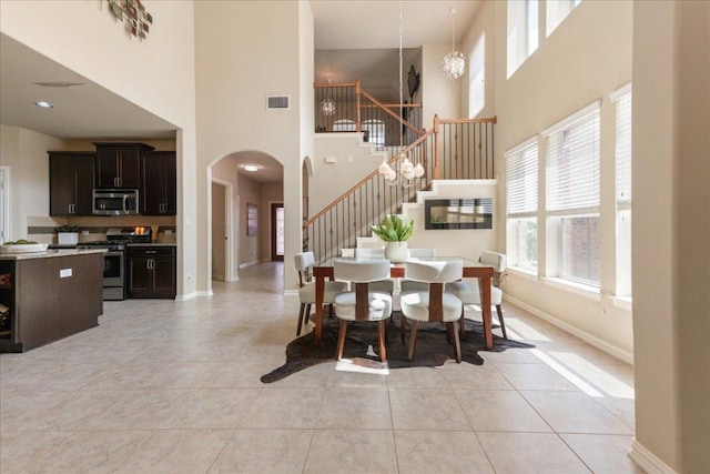 1366 Red Stag Pl, Round Rock, TX 78665 - dining area with stairway, a high ceiling, arched walkways, and light tile patterned flooring