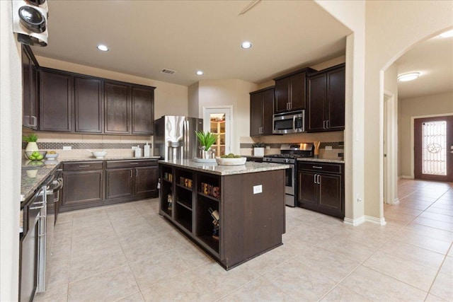 1366 Red Stag Pl, Round Rock, TX 78665 - kitchen with arched walkways, stainless steel appliances, backsplash, light tile patterned flooring, and dark brown cabinets