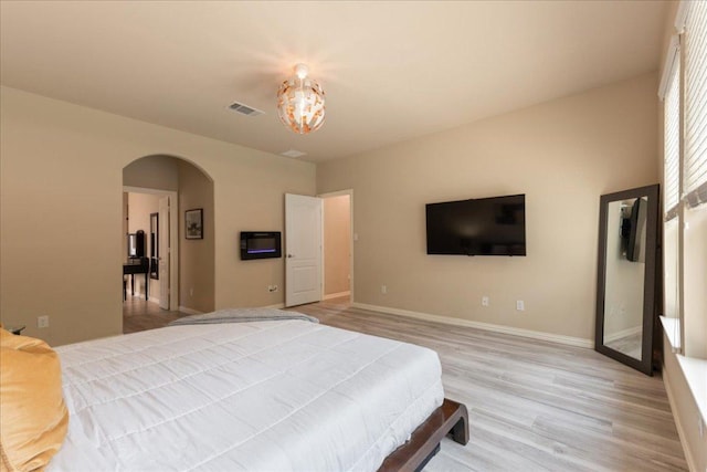 1366 Red Stag Pl, Round Rock, TX 78665 - bedroom featuring arched walkways, light wood-type flooring, and a chandelier