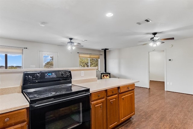 8319 County Road 200, Burnet, TX 78611 - kitchen featuring black range with electric stovetop, ceiling fan, a wood stove, brown cabinetry, and plenty of natural light