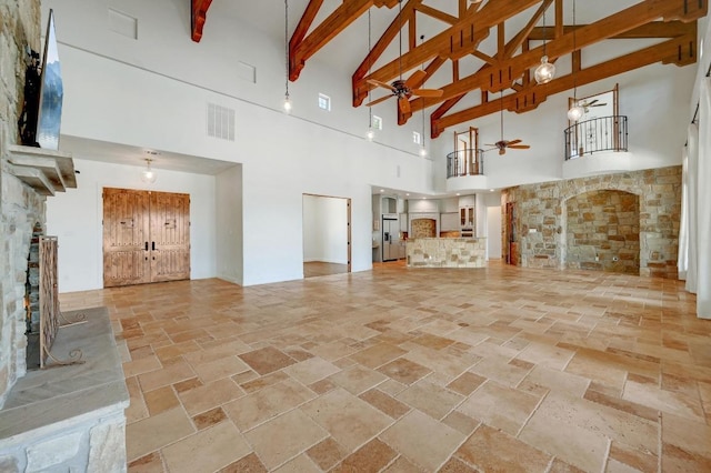 144 Serene St, Spring Branch, TX 78070 - unfurnished living room with stone tile floors, a stone fireplace, high vaulted ceiling, ceiling fan, and beamed ceiling