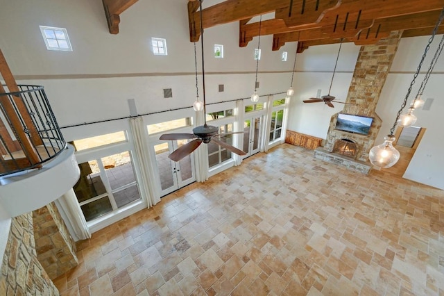 144 Serene St, Spring Branch, TX 78070 - unfurnished living room featuring ceiling fan, a high ceiling, beam ceiling, stone finish floors, and a fireplace