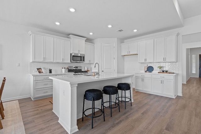 529 Leeward Pass, Leander, TX 78641 - kitchen with stainless steel appliances, tasteful backsplash, white cabinets, an island with sink, and recessed lighting