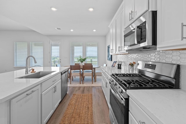 529 Leeward Pass, Leander, TX 78641 - kitchen with appliances with stainless steel finishes, dark wood-style flooring, decorative backsplash, light countertops, and recessed lighting