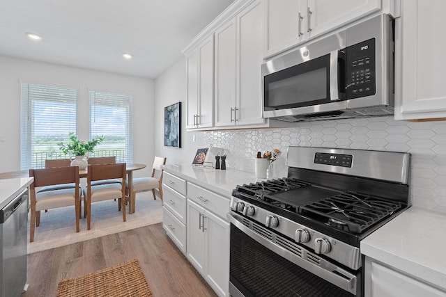 529 Leeward Pass, Leander, TX 78641 - kitchen featuring stainless steel appliances, light wood-type flooring, light countertops, white cabinets, and backsplash