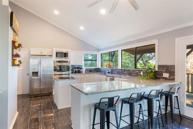 121 Kaelepulu Dr, Bastrop, TX 78602 - kitchen with stainless steel appliances, light stone countertops, tasteful backsplash, white cabinets, and a kitchen island