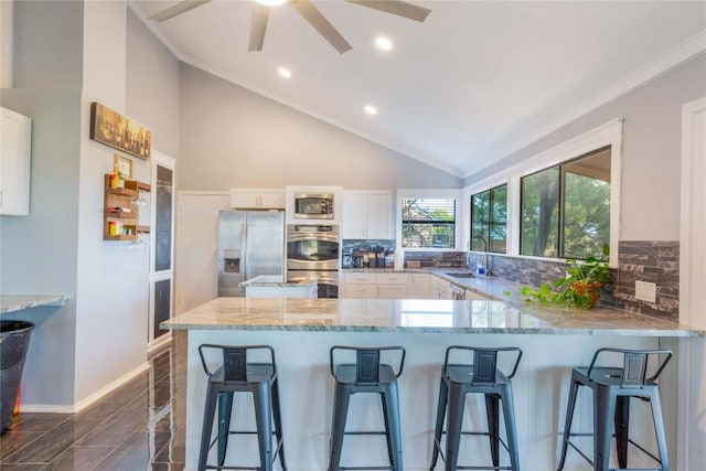 121 Kaelepulu Dr, Bastrop, TX 78602 - kitchen featuring stainless steel appliances, light stone countertops, white cabinetry, lofted ceiling, and backsplash