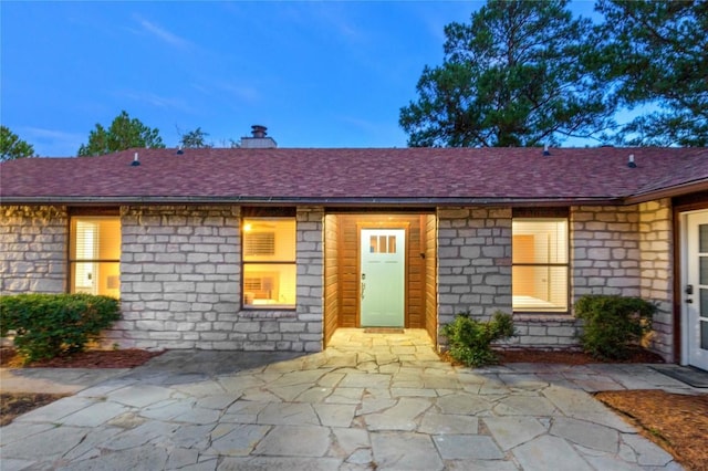 121 Kaelepulu Dr, Bastrop, TX 78602 - entrance to property featuring stone siding, a chimney, a shingled roof, and a patio area