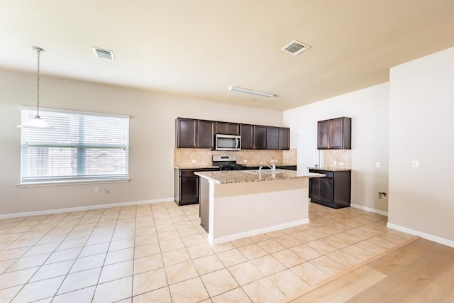 1605 Atlas Rd, Cedar Park, TX 78613 - kitchen with appliances with stainless steel finishes, decorative backsplash, an island with sink, dark brown cabinets, and light stone counters