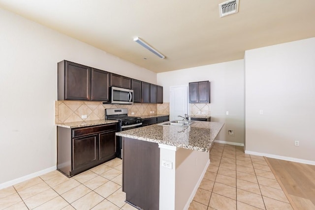 1605 Atlas Rd, Cedar Park, TX 78613 - kitchen with stainless steel appliances, a sink, decorative backsplash, light tile patterned flooring, and dark brown cabinets