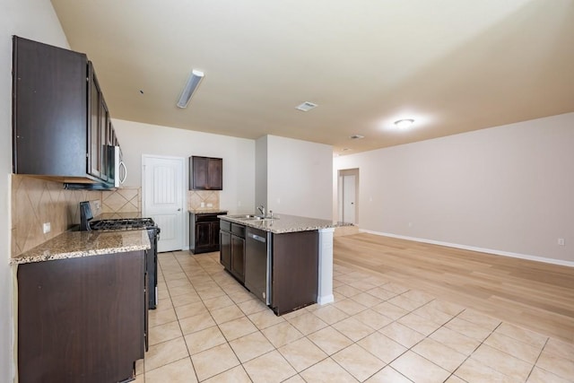 1605 Atlas Rd, Cedar Park, TX 78613 - kitchen with stainless steel appliances, backsplash, dark brown cabinetry, a center island with sink, and a sink