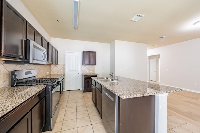 1605 Atlas Rd, Cedar Park, TX 78613 - kitchen featuring stainless steel appliances, a sink, light tile patterned floors, decorative backsplash, and an island with sink