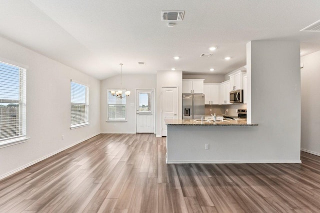 133 Nathaniel Dr, Taylor, TX 76574 - kitchen featuring stainless steel appliances, wood finished floors, a chandelier, white cabinetry, and light stone counters