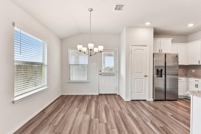 133 Nathaniel Dr, Taylor, TX 76574 - kitchen featuring stainless steel refrigerator with ice dispenser, a chandelier, light wood finished floors, white cabinetry, and light stone countertops