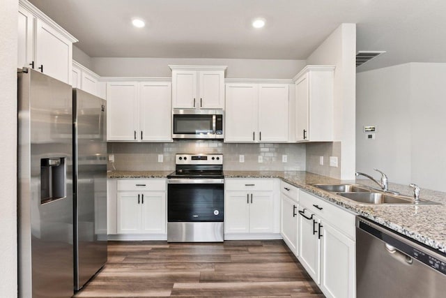 133 Nathaniel Dr, Taylor, TX 76574 - kitchen with stainless steel appliances, white cabinetry, light stone countertops, dark wood-style floors, and recessed lighting