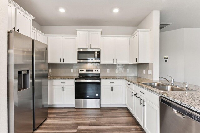 133 Nathaniel Dr, Taylor, TX 76574 - kitchen with appliances with stainless steel finishes, white cabinetry, light stone counters, dark wood-style flooring, and recessed lighting