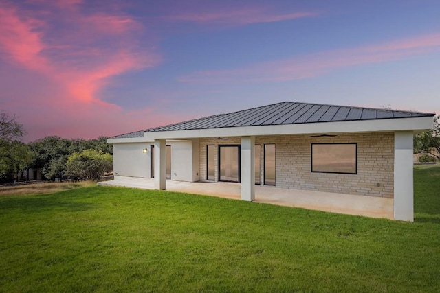 201 Custers Last Stand, Horseshoe Bay, TX 78657 - back of house at dusk with a patio, a lawn, and metal roof