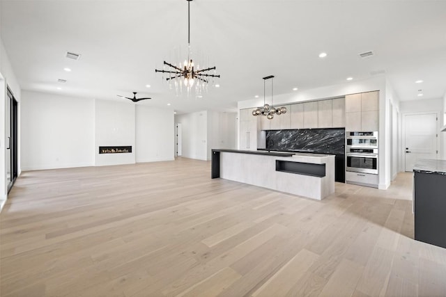 201 Custers Last Stand, Horseshoe Bay, TX 78657 - unfurnished living room featuring a chandelier, recessed lighting, light wood finished floors, a sink, and a fireplace