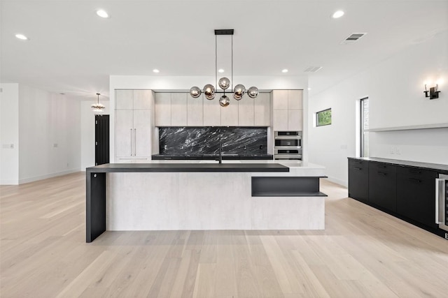 201 Custers Last Stand, Horseshoe Bay, TX 78657 - kitchen with modern cabinets, tasteful backsplash, light wood finished floors, a center island with sink, and recessed lighting