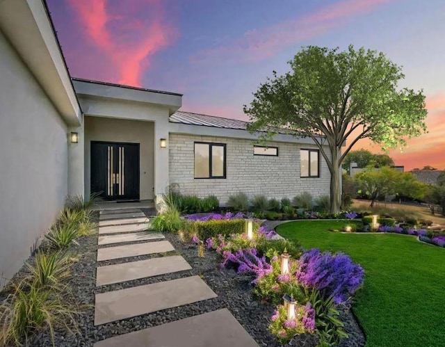 201 Custers Last Stand, Horseshoe Bay, TX 78657 - exterior entry at dusk with a yard and stucco siding