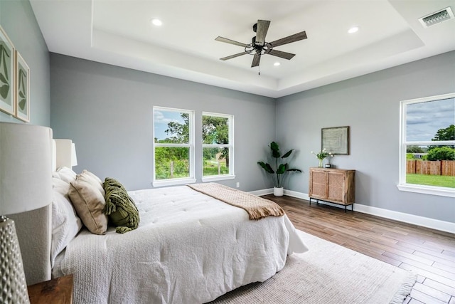 367 Stockade Ranch Rd, Paige, TX 78659 - bedroom featuring a tray ceiling, wood finished floors, multiple windows, and recessed lighting