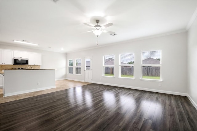 111 Colthorpe Ln, Hutto, TX 78634 - unfurnished living room featuring ornamental molding, ceiling fan, baseboards, and wood finished floors