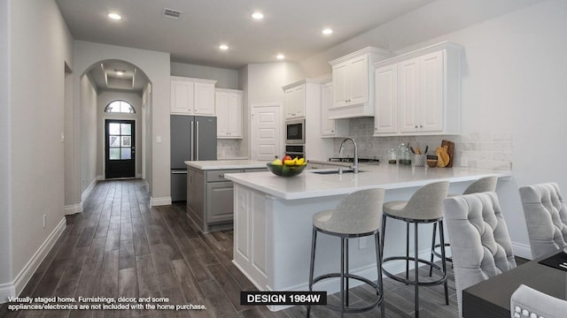 165 Plumbago Loop, Bastrop, TX 78602 - kitchen featuring stainless steel appliances, arched walkways, a peninsula, a sink, and white cabinetry