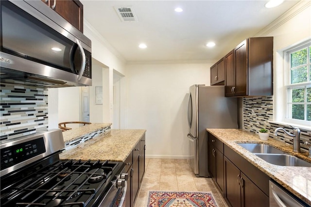 605 Orland Blvd, Austin, TX 78745 - kitchen with stainless steel appliances, a sink, ornamental molding, dark brown cabinetry, and decorative backsplash