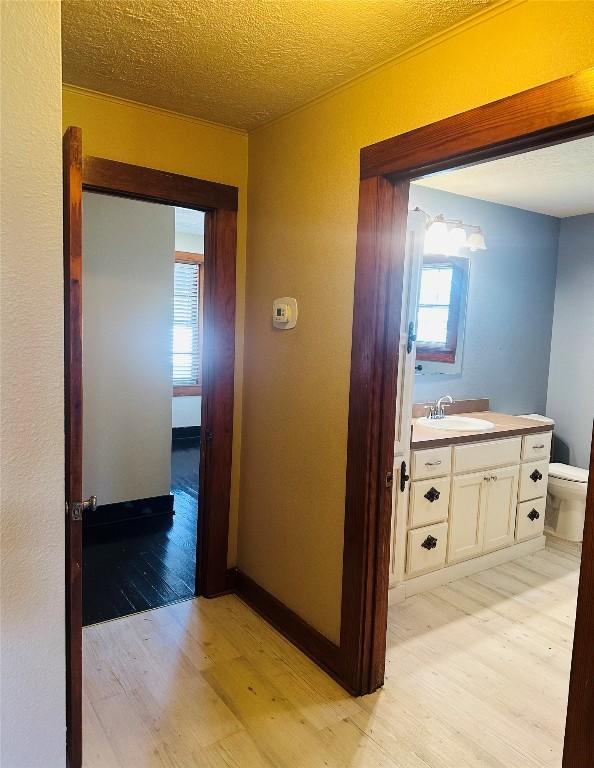 486 E Galveston St, Giddings, TX 78942 - corridor with light wood-type flooring, a sink, and a textured ceiling