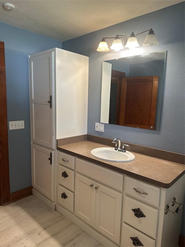 486 E Galveston St, Giddings, TX 78942 - bathroom featuring wood finished floors, vanity, and a textured ceiling