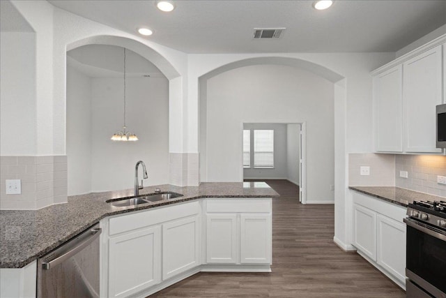 423 Leadtree Loop, Buda, TX 78610 - kitchen with appliances with stainless steel finishes, a peninsula, dark stone counters, white cabinetry, and recessed lighting