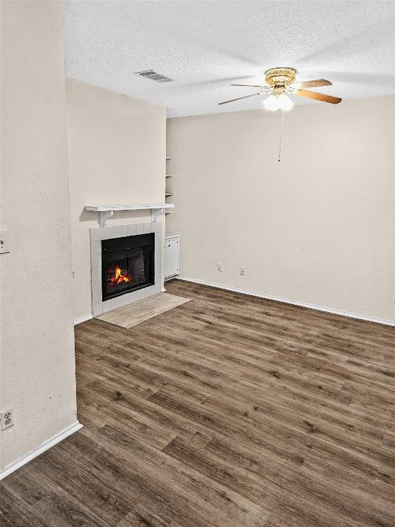 2706 Salado St Unit 205, Austin, TX 78705 - unfurnished living room featuring a ceiling fan, a tiled fireplace, wood finished floors, a textured ceiling, and baseboards