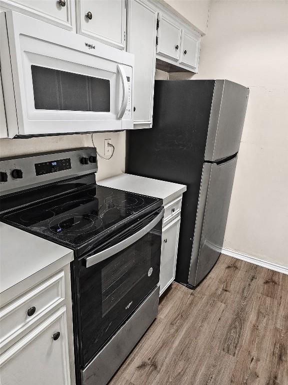 2706 Salado St Unit 205, Austin, TX 78705 - kitchen with stainless steel range with electric stovetop, white microwave, light wood-style floors, light countertops, and white cabinetry