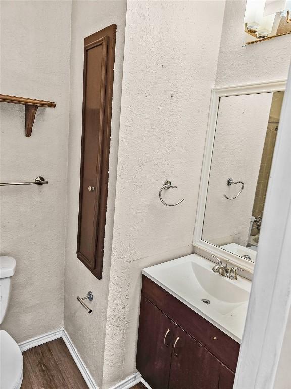 2706 Salado St Unit 205, Austin, TX 78705 - half bath with toilet, wood finished floors, vanity, a textured wall, and baseboards