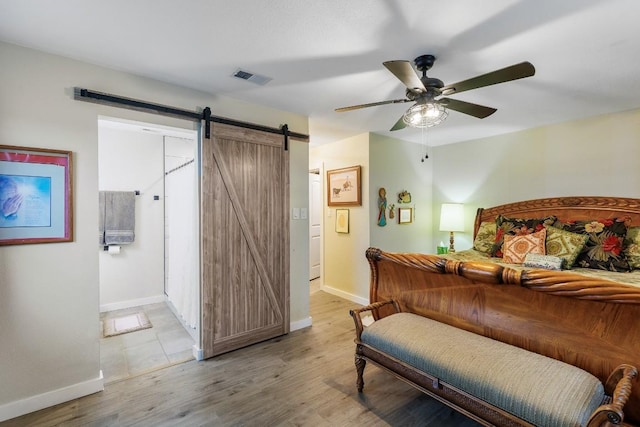 2340 E State Highway 71, Llano, TX 78643 - bedroom featuring a barn door, baseboards, wood finished floors, and ceiling fan