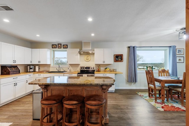 2340 E State Highway 71, Llano, TX 78643 - kitchen featuring stainless steel range with electric stovetop, a sink, wall chimney range hood, a breakfast bar, and a kitchen island
